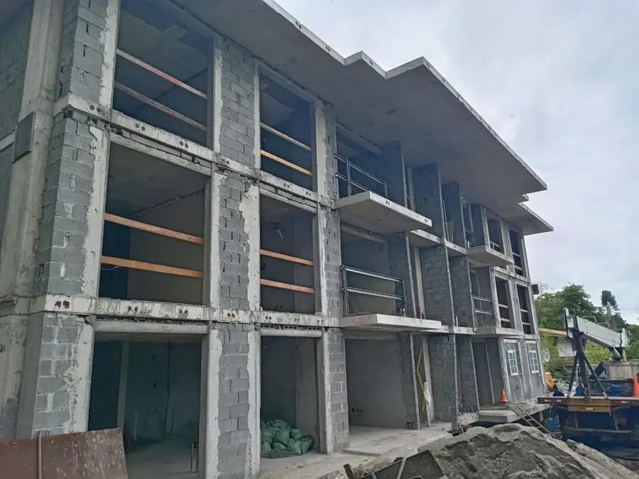 Edificio de tres niveles en obra gris, fachada frontal
